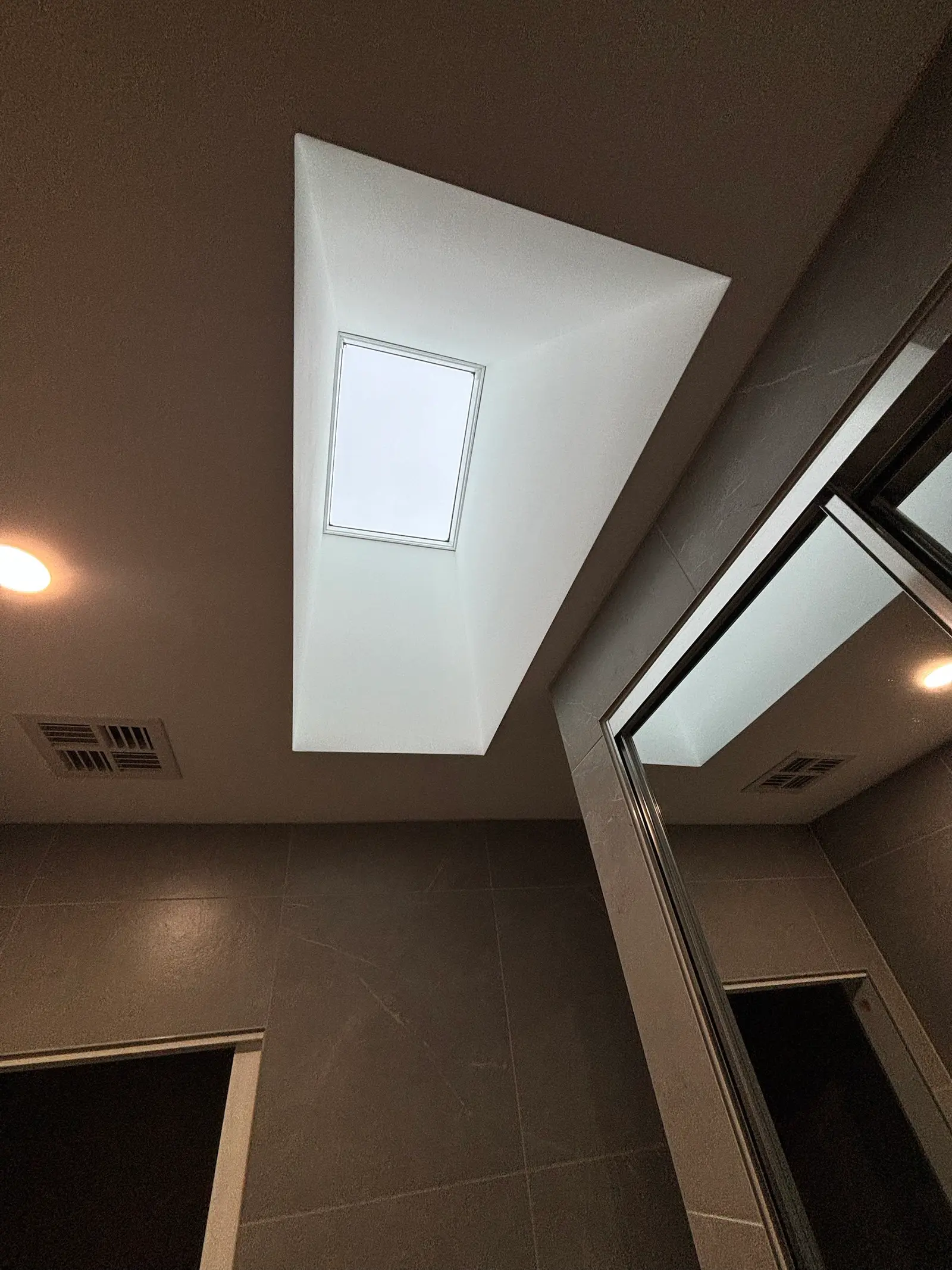 Looking up at the skylight through its splayed, white-plastered light shaft in the ensuite ceiling