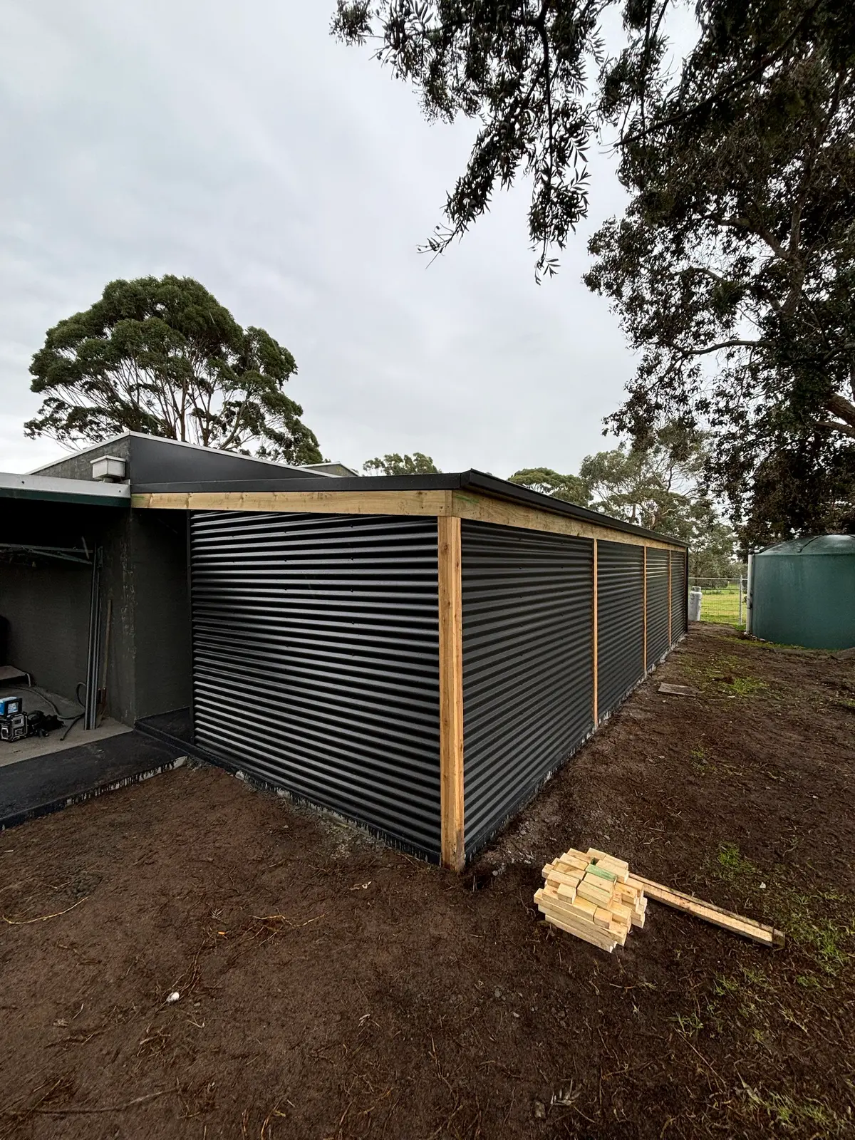 Timber-framed structure clad in dark corrugated steel with exposed timber posts